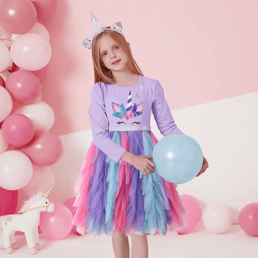 Petite fille à une fête porte une robe licorne violette avec un jupon en tulle rose bleu et violet