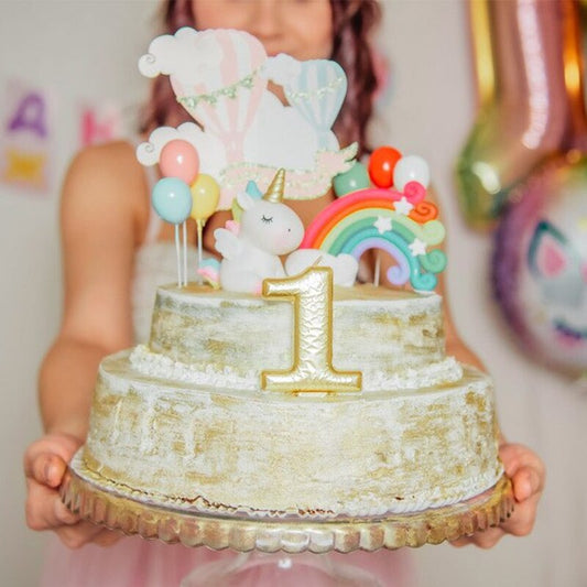 Gâteau orné de décorations licorne comprenant 6 petits ballons, une licorne miniature et un arc-en-ciel.